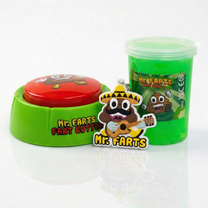 A novelty toy set featuring a green plastic tub of Fart Putty slime with a cartoon poop character on the label called Mr Farts, a Fart Button with green base and a red round button labeled 'Mr. Farts Fart Button,' and a matching cartoon Taco Farts keyring in front.