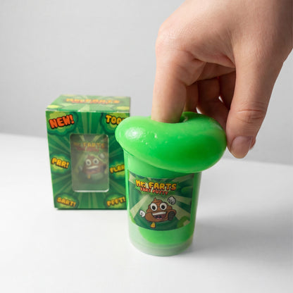 A hand is pressing a bright green, Fart Putty onto a small clear cup labeled 'Mr Farts Fart Putty.' A matching green product box stands behind it on a clean white studio background.